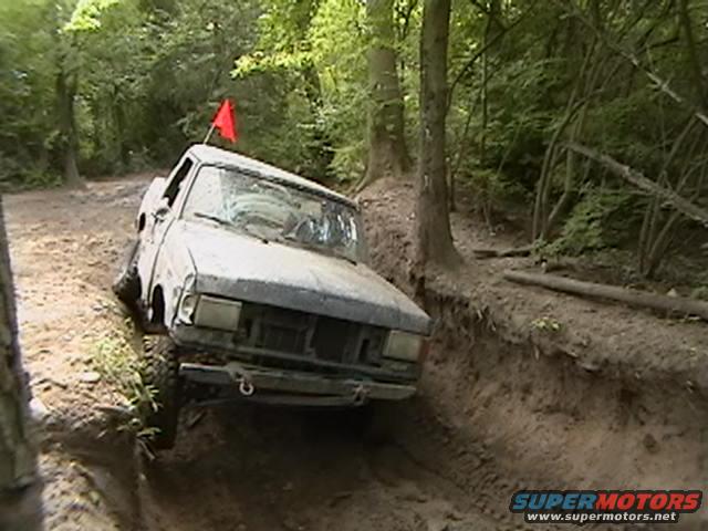 Pickup truck on muddy trail with red flag on roof