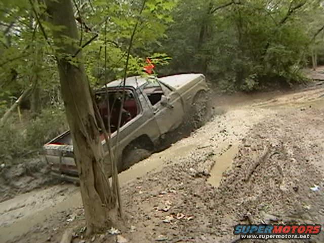 1988 Ford Bronco navigating a muddy trail, kicking up dirt