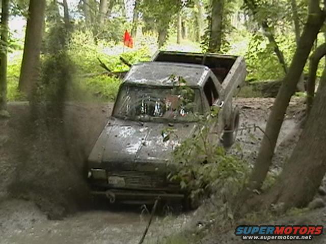 Muddy pickup truck navigating a muddy trail in a forest
