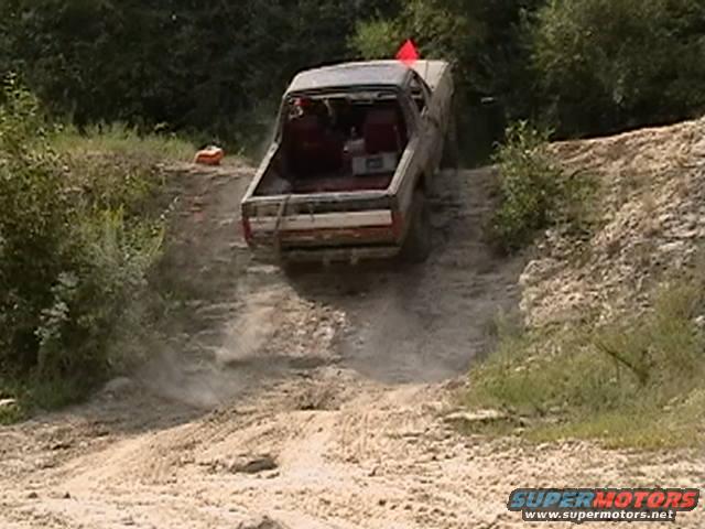 Dusty off-road truck descending a dirt hill, rear view