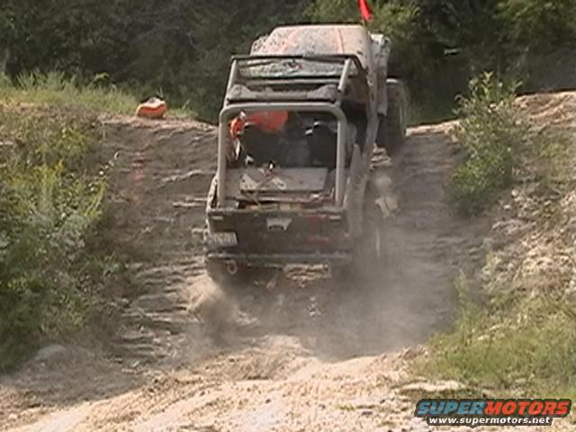 Off-road vehicle climbing dirt hill, kicking up dust