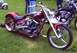1982 Ford Bronco - A custom motorcycle with intricate artwork sits on display next to another bike and a scooter.