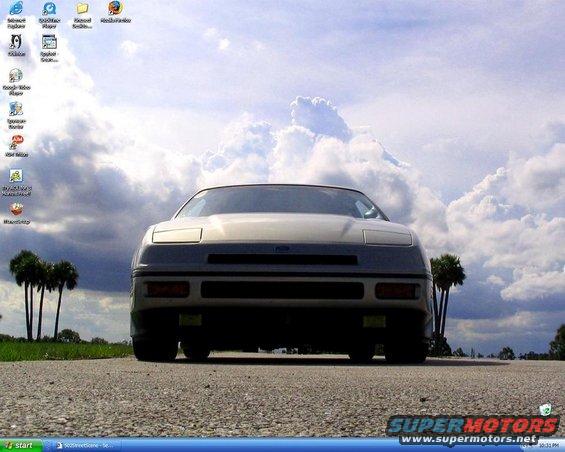 Front view of a 1989 Ford Probe parked on a road with palm trees and clouds