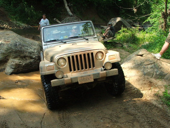 Tan Jeep Wrangler navigating muddy terrain