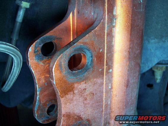 Close-up of two rusted metal suspension components with bolt holes