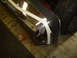 1989 Ford Bronco - Close-up of a chrome bumper section with tape, showing a reflection of a person in jeans.