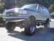 1989 Ford Bronco - This lifted 1989 Ford Bronco 4x4 features prominent off-road tires and a chrome front bumper.