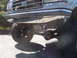 1989 Ford Bronco - Close-up of a gray Ford truck's front end, showing the grille, bumper, and suspension components.