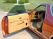 1979 Ford Ranchero - The interior of an orange pickup truck shows tan upholstery and a dashboard with a prominent steering wheel.