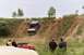 1979 Ford Bronco - A blue pickup truck navigates a steep dirt hill while onlookers watch from a red vehicle.