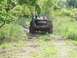 1979 Ford Bronco - A black Ford Bronco navigates a muddy trail with two occupants visible in the cabin.