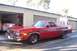 1973 Ford Ranchero - A red 1977 Ford Ranchero is parked outside a garage, with another vehicle visible inside.