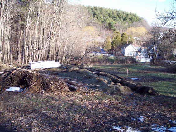White trailer with a single axle parked on a grassy area with debris