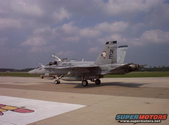Gray F/A-18F Super Hornet with 'NE' and skull insignia on tail, parked on tarmac