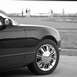 2002 Ford Thunderbird - A black 2002 Ford Thunderbird convertible is shown from the front passenger side, with chrome wheels and people in the background.