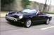 2002 Ford Thunderbird - A black 2002 Ford Thunderbird convertible is captured in motion on a paved road.