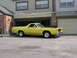 1978 Ford Ranchero - Yellow 1978 Ford Ranchero with a black hood is parked in front of a residential garage.