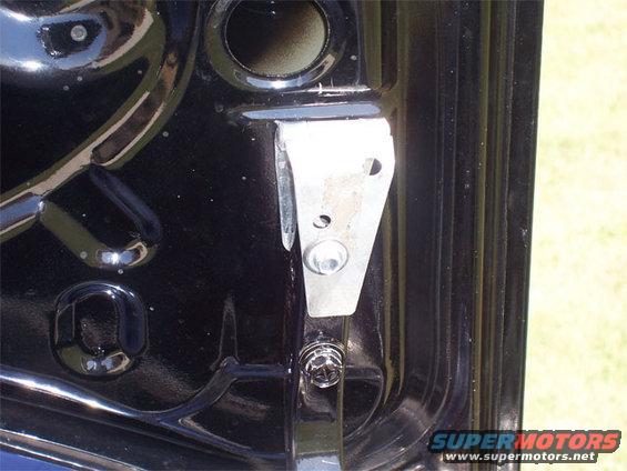 Black car body with a silver metal bracket attached by a bolt. Visible text 'SUPER MOTORS'