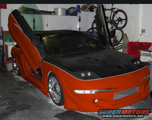 Orange and black 1994 Ford Probe with butterfly doors open, custom body kit, and aftermarket wheels