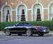 2002 Ford Thunderbird - A black 2002 Ford Thunderbird convertible is parked in front of a brick building with large arched windows.