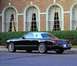 2002 Ford Thunderbird - The rear view of a black 2002 Ford Thunderbird convertible with a white hardtop, parked in front of a brick building.