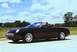 2002 Ford Thunderbird - A black 2002 Ford Thunderbird convertible cruises down the highway under a cloudy sky.