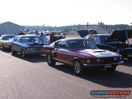 Maroon 1968 Shelby GT500 Mustang and other classic cars at a drag strip