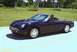 2002 Ford Thunderbird - A black 2002 Ford Thunderbird convertible is captured in a three-quarter front view while driving on a sunny day.