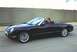 2002 Ford Thunderbird - A black 2002 Ford Thunderbird convertible is captured in a side profile shot while driving on a road.