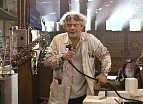 Man wearing lab coat and goggles, holding a device with a cord