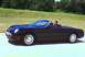 2002 Ford Thunderbird - A man drives a black 2002 Ford Thunderbird convertible down a highway with trees in the background.