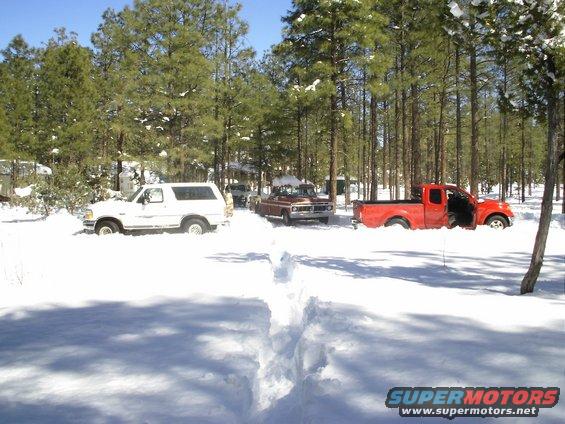 White SUV and two pickup trucks partially buried in snow