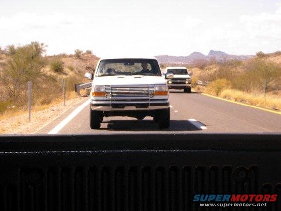 two white trucks driving on a highway in a desert landscape