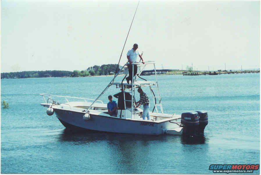 Fishing boat with people on the water, two outboard motors visible at the stern