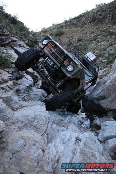Green 1966 Ford Bronco tilted on rocky terrain