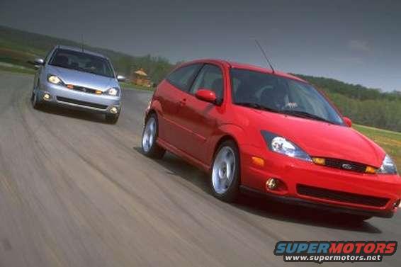 Red 2002 Ford Focus SVT driving on a track with a silver Focus behind it