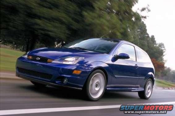 Blue two-door hatchback car driving on a road, front 3/4 view. Visible text: SUPERMOTORS www.supermotors.net