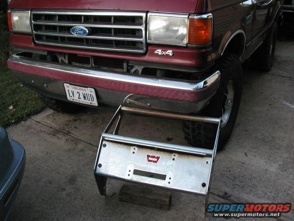 Red Ford truck front with chrome bumper, Virginia license plate LY 2 MUD, and a detached Warn winch bumper assembly