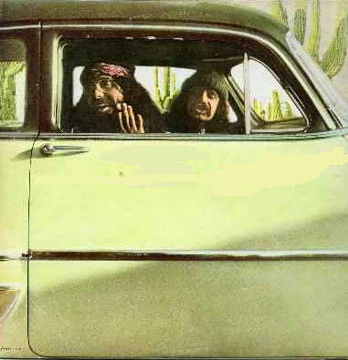 Side view of a light green vintage car with two men inside, one wearing a headscarf