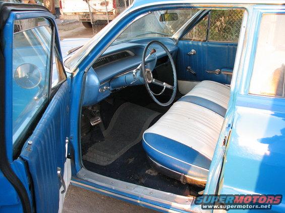 Blue and white interior of a vintage station wagon, showing dashboard, steering wheel, and two-tone seats