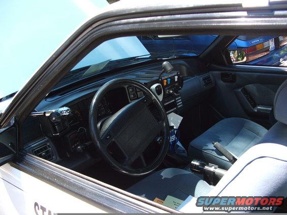 1987 Ford Mustang police car interior with steering wheel, dashboard, and seats