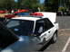 1987 Ford Mustang - A white Ford Mustang police car is shown at an outdoor event, with its hood and trunk open, alongside other cars.