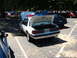 1987 Ford Mustang - A white police car with its trunk and hood open is parked in a lot, with other vehicles visible in the background.