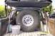 1989 Ford Bronco - The rear interior of a vehicle is shown, a large spare tire mounted vertically and a custom roll cage structure.