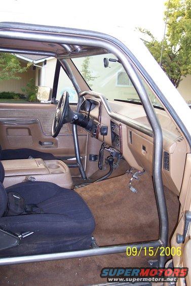 Interior of a vehicle with a roll cage, showing the dashboard, steering wheel, and seats
