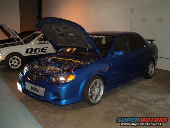 Blue sedan, hood open, showing engine and HKS grille