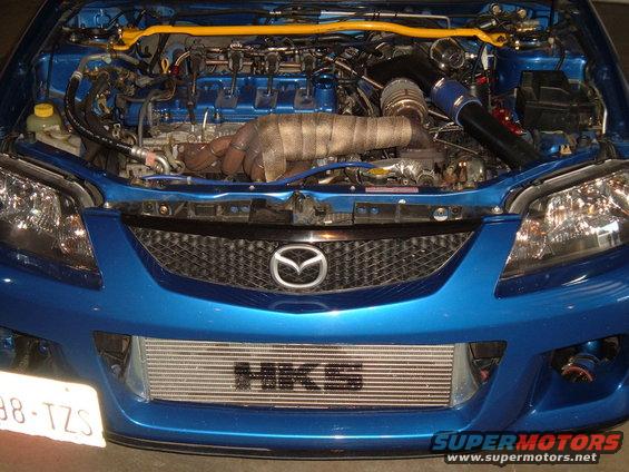 Blue Mazda with engine bay open, showing turbo, intercooler, and exhaust manifold