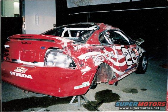 Red 1995 Ford Mustang race car, heavily damaged, with racing decals and number 26