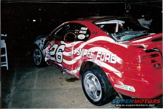 1995 Ford Mustang race car with "SNIPES FORD" and "26" graphics, showing damage to the body and windshield