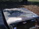 1988 Ford Bronco - The hood of a truck displays a worn camouflage paint job with visible primer and rust patches.